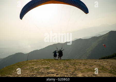 Eine Paragliding-Lehrer hilft einen Schirm gegen die Sonne in luftigen ausziehen, Bir Billing, Himachal Pradesh, Indien Stockfoto