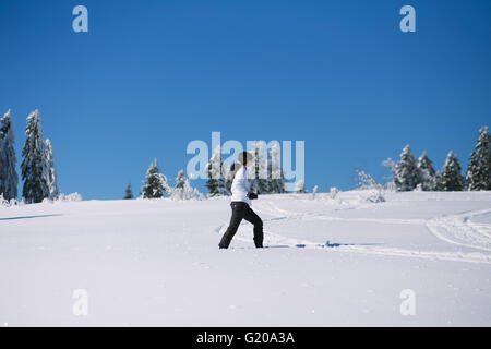 junge Frau, die zu Fuß durch den Schnee Stockfoto