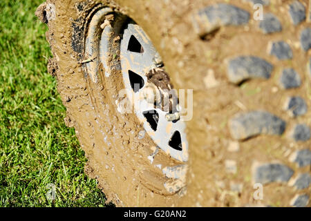 Großes Fahrzeug vom Straßenrad und Reifen voller Schlamm auf dem grünen Rasen Stockfoto