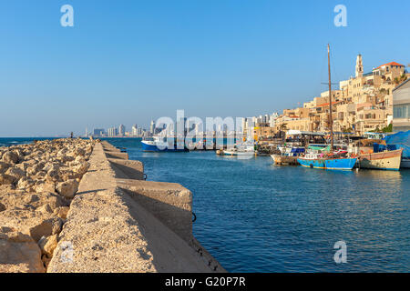 Blick vom Wellenbrecher am kleinen Hafen mit Booten, alten Jaffa und Tel Aviv auf Hintergrund unter blauem Himmel in Israel. Stockfoto