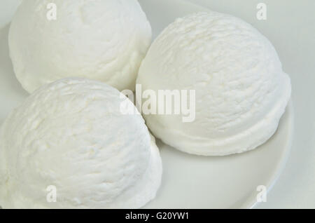 drei Kugeln weißen Eis, Vanille, Zitrone, Kokos, Joghurt oder Buttermilch Geschmack, auf weißen Teller, Nahaufnahme, Stockfoto