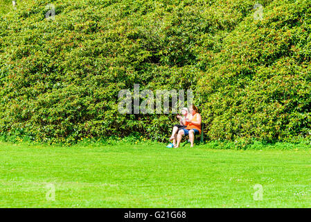 Ronneby, Schweden - 8. Mai 2016: Echte Menschen im Alltag. Hier zwei Frauen sitzen in der Nähe einer grossen Rhododendron Büsche während Stockfoto