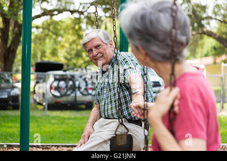 Senior paar halten die Hände auf schwingen Park Spaß Stockfoto