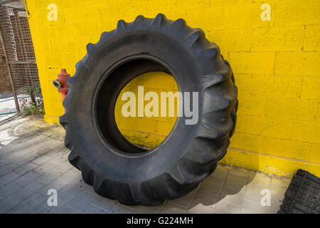 Große Reifen eine gelbe Wand gelehnt Stockfoto