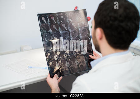 Junge männliche Arzt lesen und Überprüfung einen MRI Gehirn-scan Stockfoto