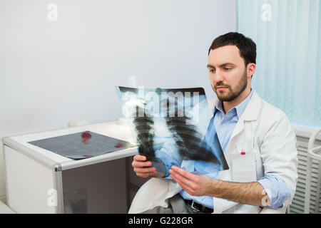 Gesundheit und Stimmung. Beim Sitzen an einem Tisch im Krankenhaus hält Ernst Doktor im Gespräch mit Patienten Röntgen in Händen. Stockfoto