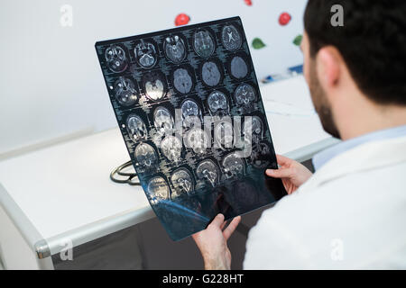 Junge männliche Arzt lesen und Überprüfung einen MRI Gehirn-scan Stockfoto