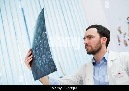 Closeup Portrait des Pflegepersonals intellektuellen Mann mit weißen Laborkittel Gehirn Röntgen Röntgenbild, Ct-Scan, mri, Klinik-Office-Hintergrund zu betrachten. Radiologie Stockfoto