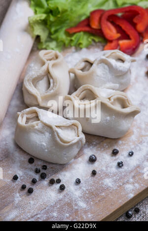 Haufen von hausgemachte rohe Khinkali Knödel Closeup mit Gemüse auf dem Brett Stockfoto