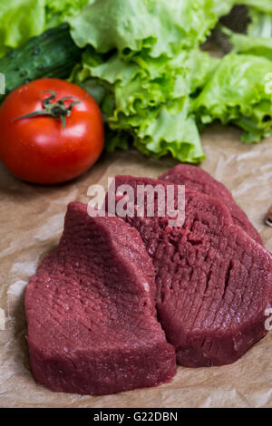 Rohes Fleisch grillen mit frischem Gemüse Holzoberfläche. Essen, Steak, Rindfleisch Bbq, Tomaten, Paprika, Gewürze zum Kochen. Stockfoto
