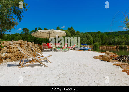 zwei gestreiften Liegestühlen am Strand Stockfoto