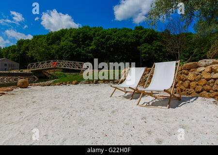 zwei gestreiften Liegestühlen am Strand Stockfoto