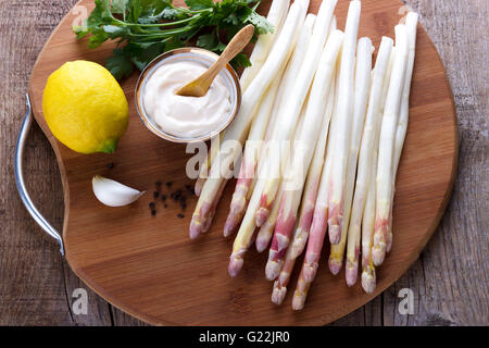 Geschälten Spargel und Zutaten für eine Soße auf Holzbrett Stockfoto