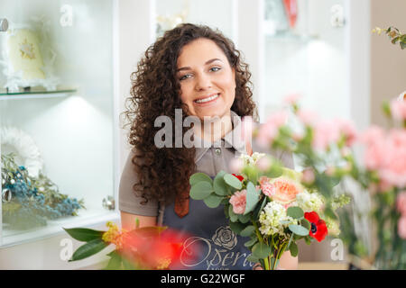 Fröhliche, schöne junge Frau Floristen bei der Arbeit im Blumenladen Stockfoto