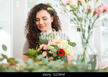 Porträt von schönen lockigen jungen Frau Floristen mit Blumenstrauß arbeitet in shop Stockfoto