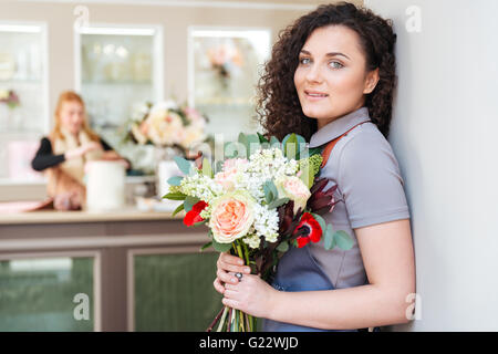 Porträt von Floristen gerne hübsche junge Frau mit Blumenstrauß im Blumenladen Stockfoto