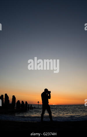 Aberystwyth Wales UK, Montag, 23. Mai 2016 UK Wetter: ein Mann am Strand fotografieren ist Silhouette gegen einen spektakulären Sonnenuntergang über Cardigan Bay in Aberystwyth an der Westküste Wales UK.   Bildnachweis: Keith Morris / Alamy Live News Stockfoto