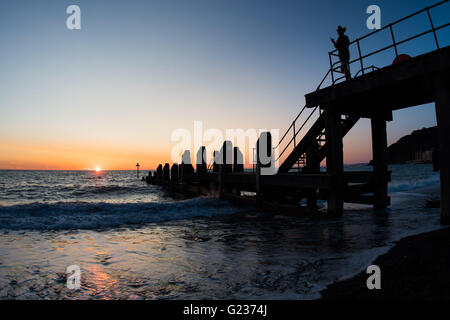 Aberystwyth Wales UK, Montag, 23. Mai 2016 UK Wetter: Menschen, die einen Abendspaziergang auf dem Holzsteg am Meer sind Silhouette gegen einen spektakulären Sonnenuntergang über Cardigan Bay in Aberystwyth an der Westküste Wales UK.   Bildnachweis: Keith Morris / Alamy Live News Stockfoto