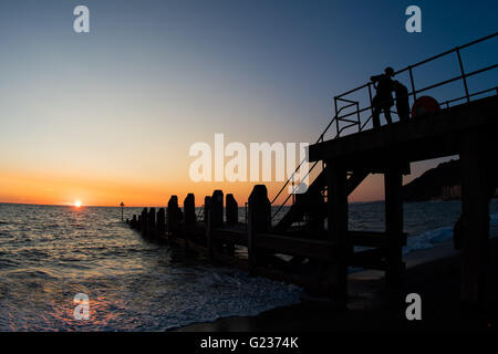 Aberystwyth Wales UK, Montag, 23. Mai 2016 UK Wetter: Menschen, die einen Abendspaziergang auf dem Holzsteg am Meer sind Silhouette gegen einen spektakulären Sonnenuntergang über Cardigan Bay in Aberystwyth an der Westküste Wales UK.   Bildnachweis: Keith Morris / Alamy Live News Stockfoto