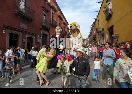 San Miguel De Allende, Mexiko. 18. April 2016. Ein paar Küsse während einer Hochzeit Parade durch die Straßen in San Miguel de Allende. Die Hochzeit-Parade ist komplett mit feierlichen Esel, eine Mariachi-Band und riesige Papier Papiermache Bildnisse (Mojigangas). (Kredit-Bild: © Julie Rogers / via ZUMA Draht) Stockfoto