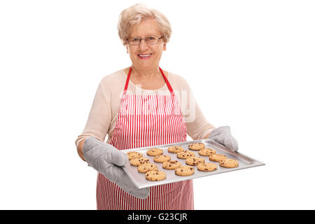 Fröhliche Reife Dame mit einem Tablett voller hausgemachten Schokoladenkekse isoliert auf weißem Hintergrund Stockfoto