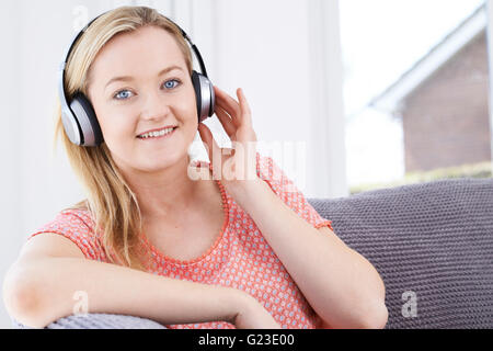 Junge Frau, die über drahtlose Kopfhörer Musik hören Stockfoto