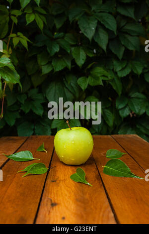 Apple im Dorf auf einem Holztisch und gefallenen Blätter im Herbst Stockfoto