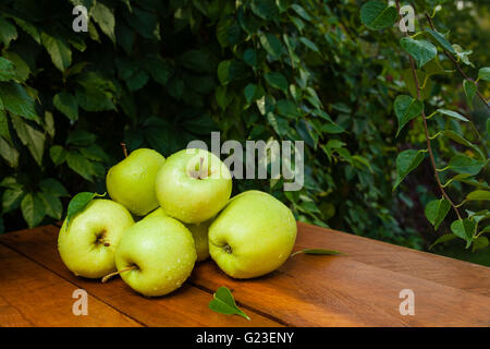 Ein paar Äpfel im Dorf auf einem Holztisch und gefallene Herbstlaub Stockfoto