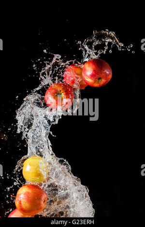 Ein paar rote Äpfel, fliegen im Raum mit dem Wasser auf einem schwarzen Hintergrund Stockfoto