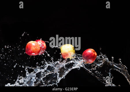 Rote Äpfel, Fliegen im Raum mit dem Wasser auf schwarzem Hintergrund Stockfoto