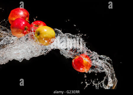 Ein paar rote Äpfel, fliegen im Raum mit dem Wasser auf einem schwarzen Hintergrund Stockfoto