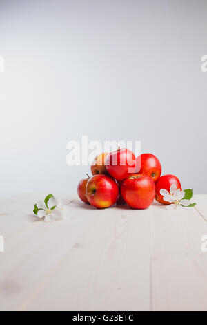 einige Äpfel auf einer weißen Holzoberfläche mit Blumen Stockfoto