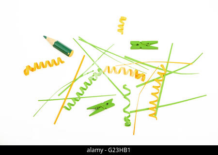 Gemischte bunte grüne und gelbe Papierstücke, Clips, Bleistifte und hölzerne bemalte Wäscheklammern isoliert auf weißem Hintergrund Stockfoto