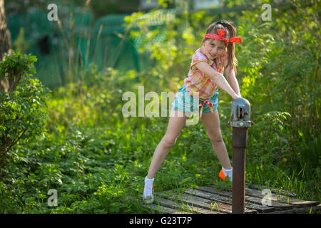 Kleines Mädchen in der Nähe der Wasserpumpe im Dorf. Stockfoto