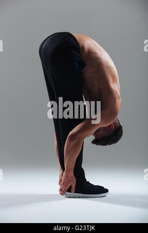 In voller Länge Portrait eines jungen Mannes, die Yoga-Übungen auf grauem Hintergrund Stockfoto