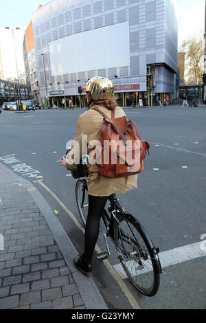 Junge weibliche Radfahrer mit einem goldenen Helm und Leder Rucksack auf dem Fahrrad warten an Ampel auf Goswell Road & Old Street in London UK KATHY DEWITT Stockfoto