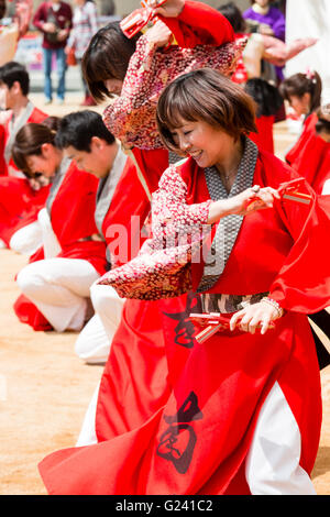 Japanische hinokuni Yosakoi Dance Festival. Dance Team, vor allem junge Frauen, Tanzen in leuchtend roten yukata Jacken und Holding naruko, hölzerne Klöppel. Stockfoto