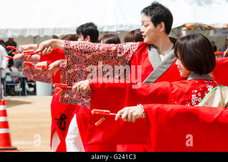 Japanische hinokuni Yosakoi Dance Festival. Dance Team, vor allem junge Frauen, Tanzen in leuchtend roten yukata Jacken und Holding naruko, hölzerne Klöppel. Stockfoto