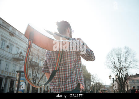 Hintere Ansicht Porträt eines Mannes zu Fuß mit Gitarre im freien Stockfoto