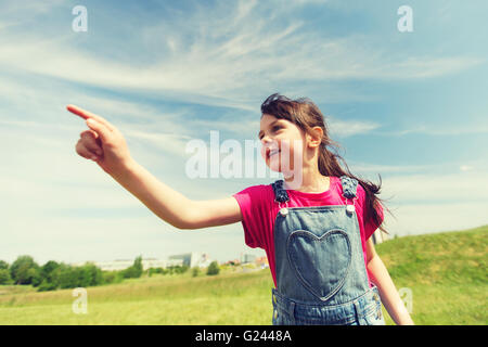 glückliche kleine Mädchen Zeigefinger auf Sommerwiese Stockfoto