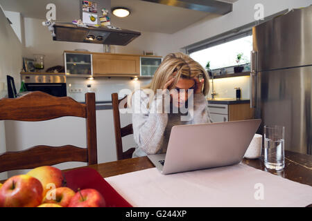 Distraught Frau mittleren Alters vor einem Laptop. Stockfoto