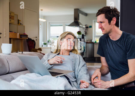 Mann und Frau die Zeit gemeinsam Vor dem Laptop sitzend auf und in der Nähe der Couch. Stockfoto