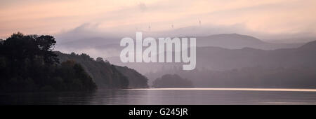 Sonnenuntergang über Coniston Water mit Windkraftanlagen auf Kirkby Moor in der Ferne, Cumbria. Stockfoto