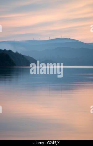 Sonnenuntergang über Coniston Water mit Windkraftanlagen auf Kirkby Moor in der Ferne, Cumbria. Stockfoto