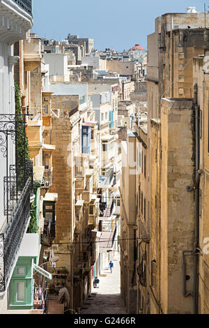 Person in engen Straße mit hohen Gebäuden, Valletta, Malta Stockfoto