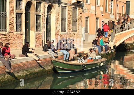 Junge Menschen genießen einen sonnigen Tag an einem Kanal in Venedig im Frühjahr Stockfoto