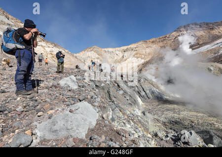 Gruppe Fotografen nimmt ein Bild Vulkanlandschaft und aktive Fumarolen, auswerfen, Dampf und Gas im Krater des aktiven Vulkans. Stockfoto