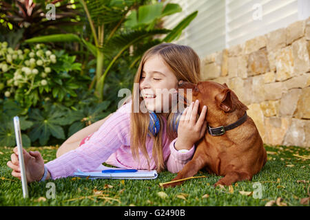 Blonde junge Mädchen Selfie Foto mit TabletPC und Hund liegen auf dem Rasen Stockfoto