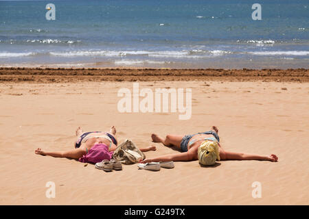 Zwei Frauen mit überdachten Köpfen Sonnenbaden am Strand, Salou, Katalonien, Spanien Stockfoto