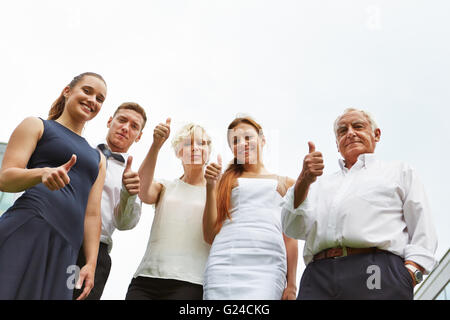 Erfolgreiches Team Daumen hochhalten und lächelnd Stockfoto